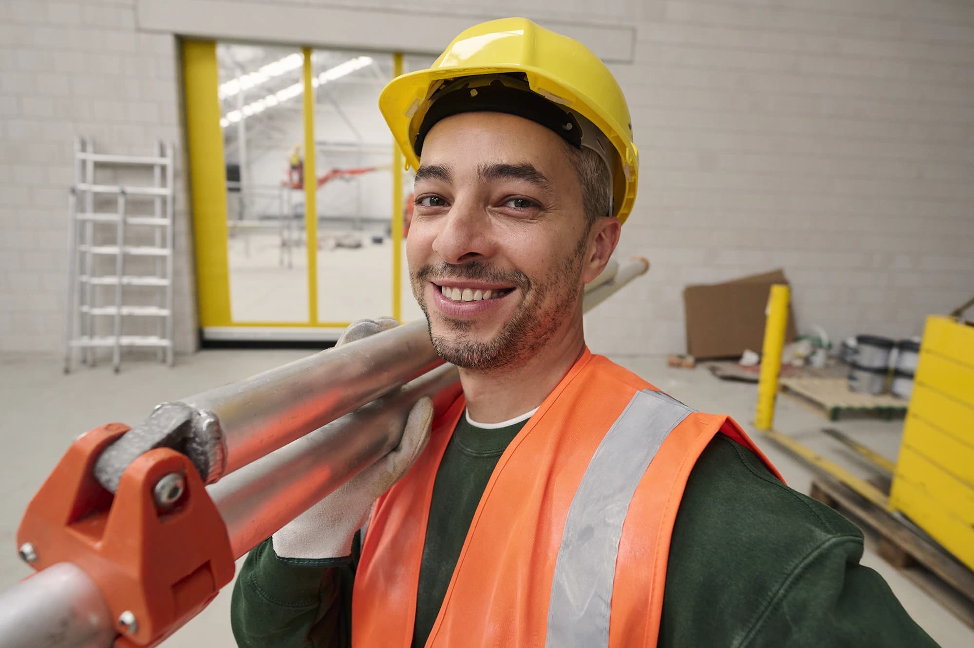 Bouwvakker met helm en fluovest glimlacht op werf — jobs in bouwsector via Accent